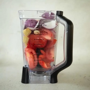 tomatoes, onions, and other vegetables in a blender